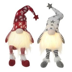Two Christmas-themed gnomes on a stand with a decorated tree in the background.